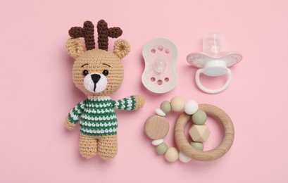 Flat lay composition with pacifiers and other baby stuff on pink background