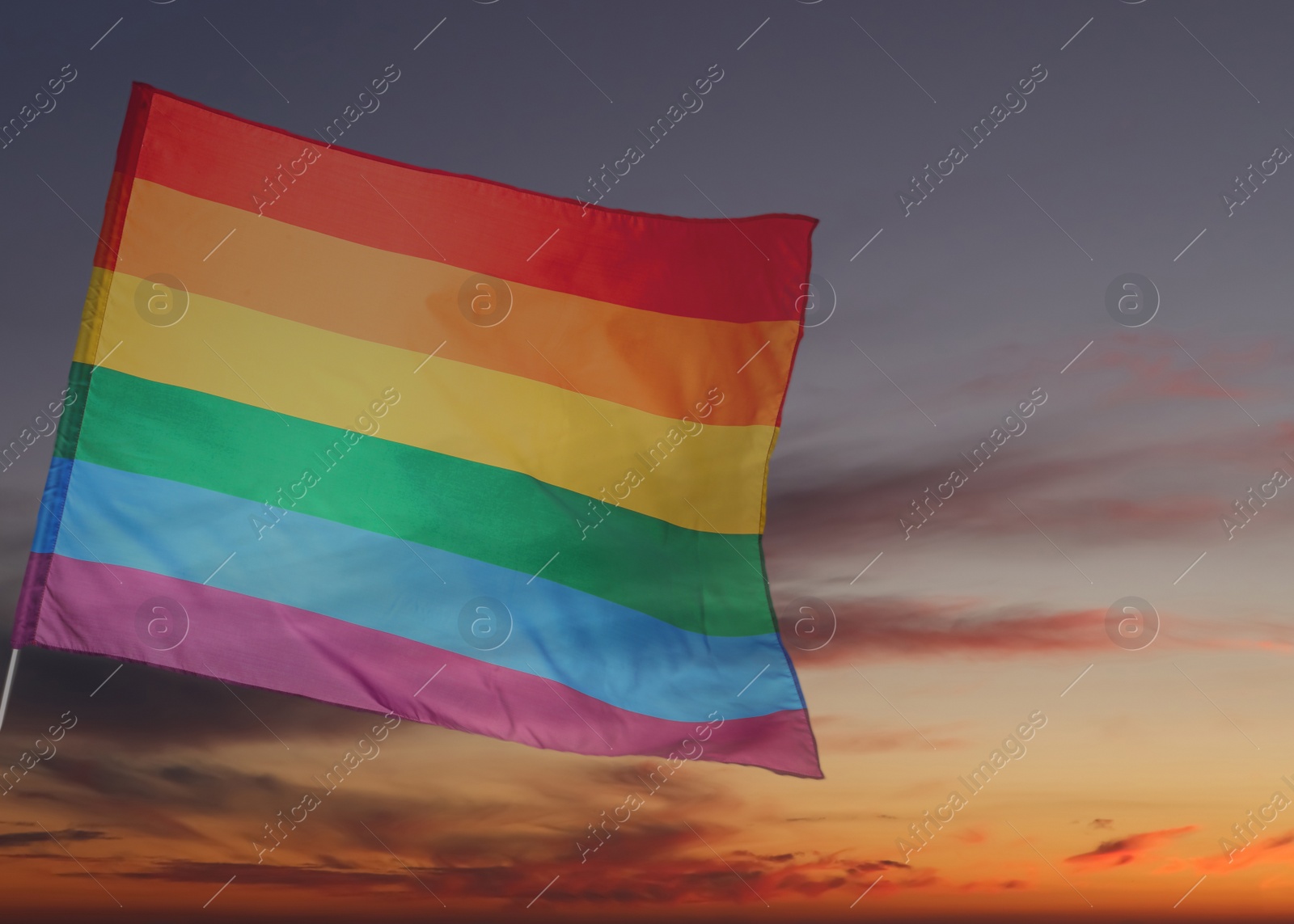 Image of Bright rainbow LGBT flag against sky at sunset