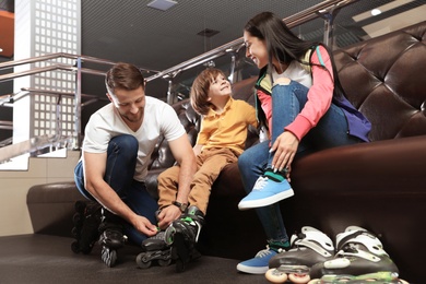Photo of Happy family putting on roller skates indoors
