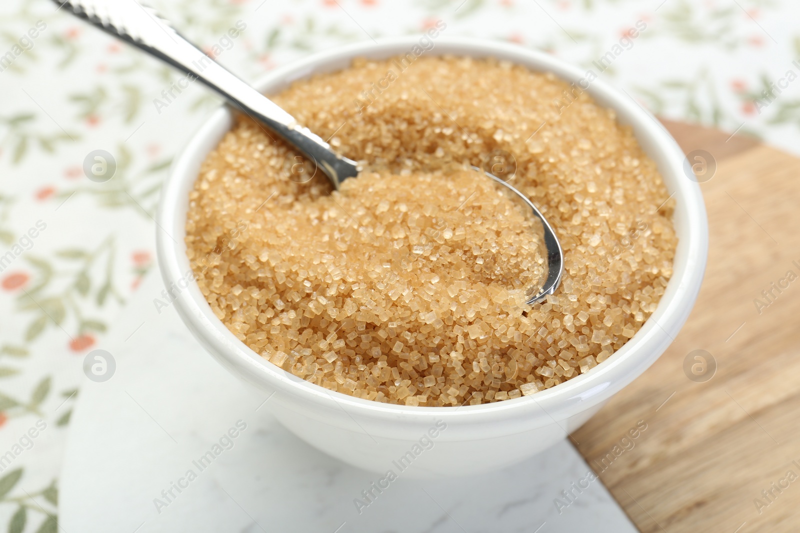 Photo of Brown sugar in bowl and spoon on table, closeup