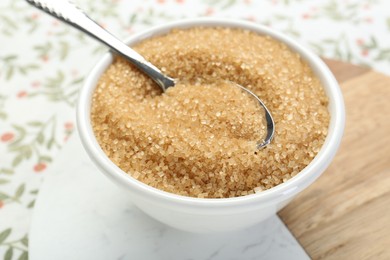 Brown sugar in bowl and spoon on table, closeup