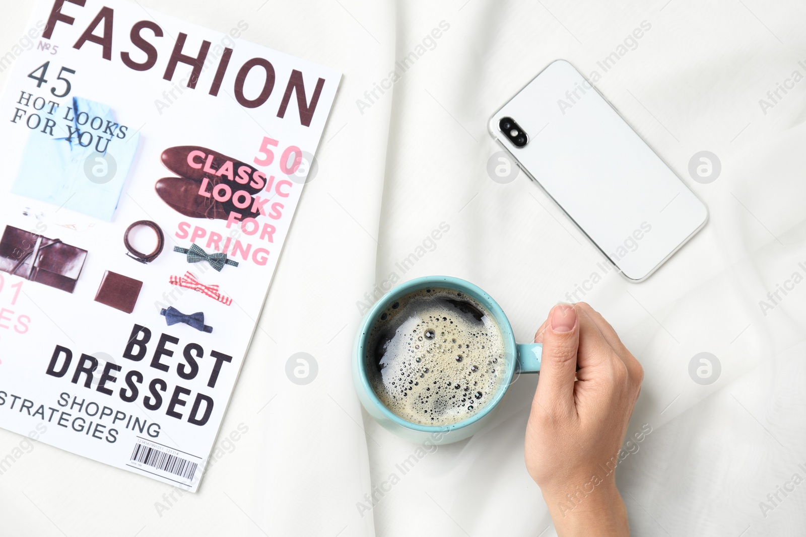 Photo of Young woman with cup of delicious coffee at table, top view