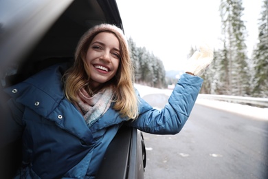 Photo of Young woman driving car and looking out of window on road. Winter vacation