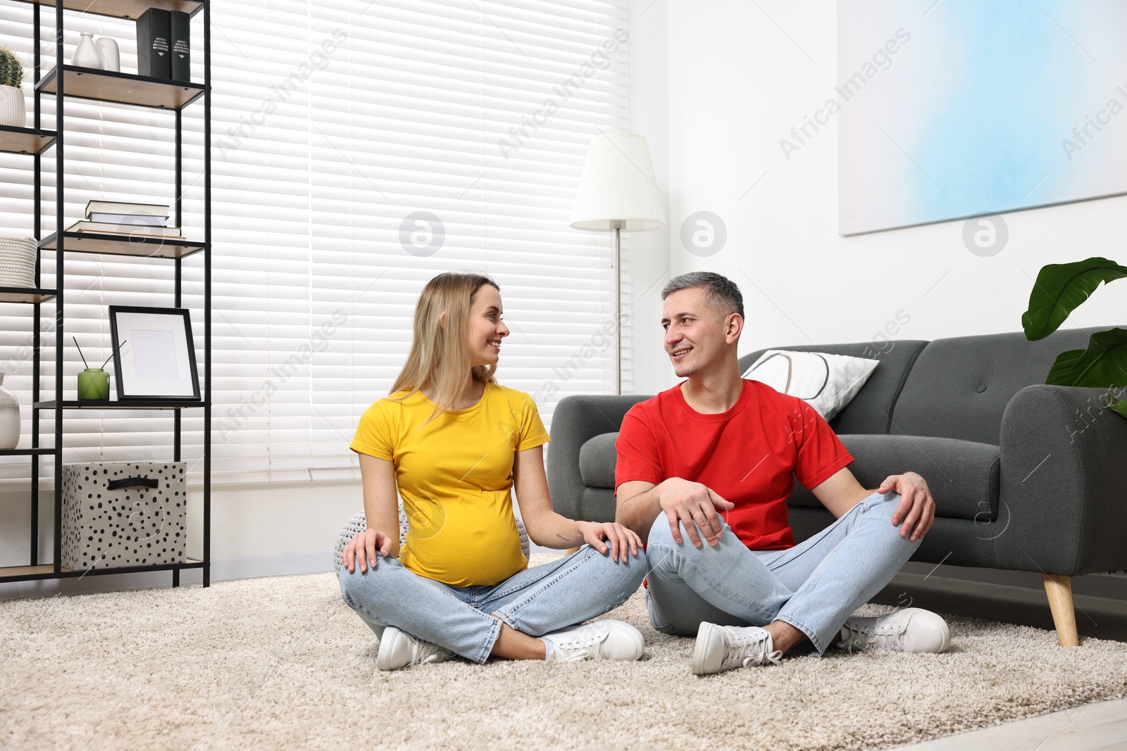 Photo of Young family housing concept. Pregnant woman with her husband on floor at home