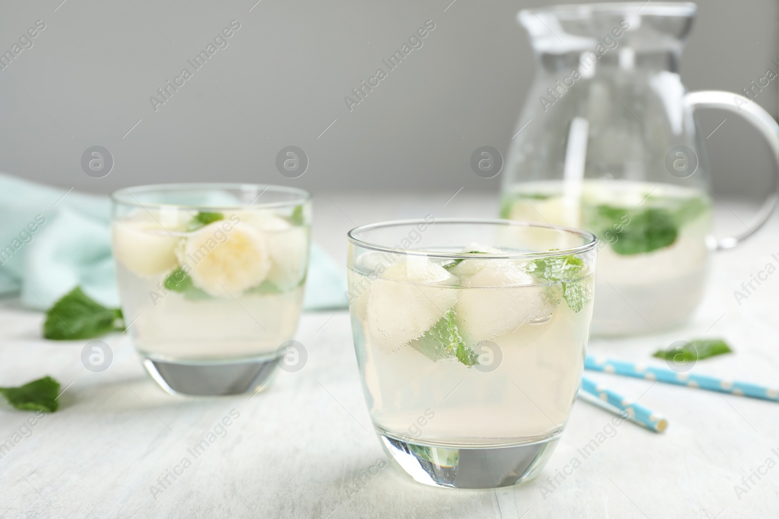 Photo of Glasses with tasty melon ball drinks on light table