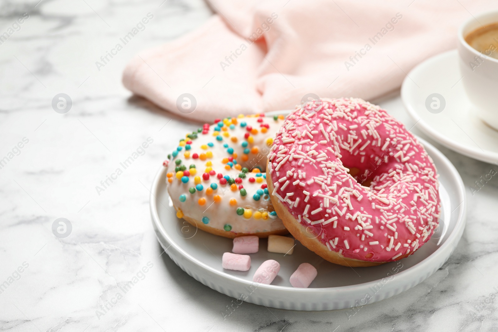 Photo of Yummy donuts with sprinkles on white marble table, closeup