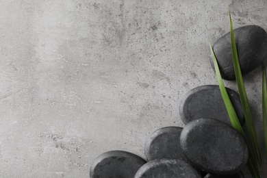 Photo of Spa stones and palm leaf on grey table, flat lay with space for text