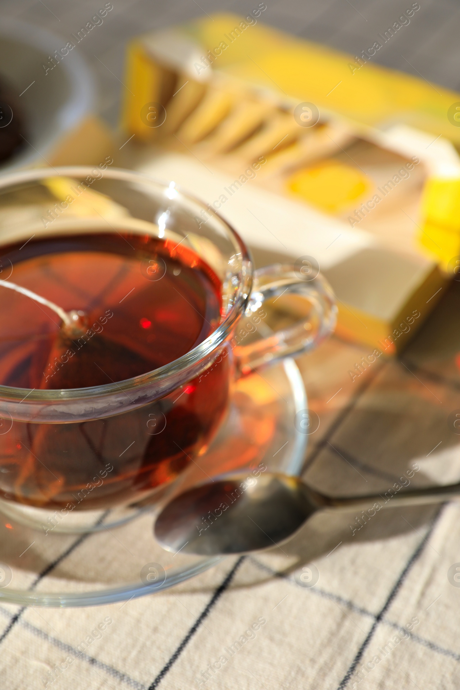 Photo of Tea bag in glass cup on table, closeup