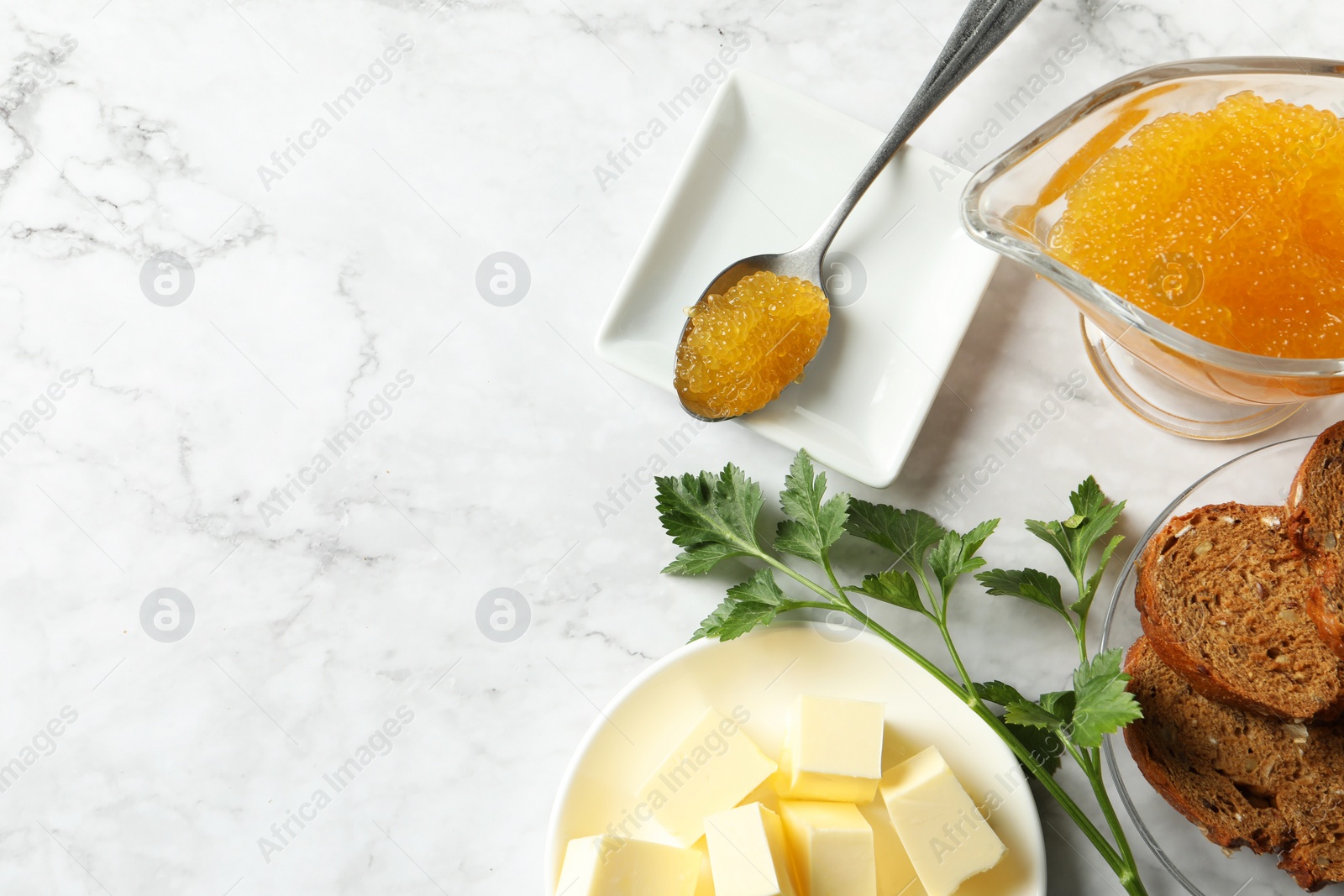 Photo of Fresh pike caviar, butter, bread and parsley on white marble table, flat lay. Space for text