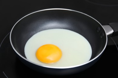 Photo of Cooking tasty egg with yolk in frying pan, closeup