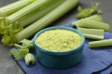 Photo of Natural celery powder in bowl and fresh stalks on grey table, closeup