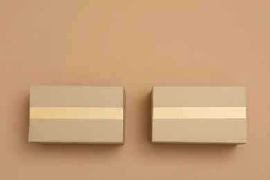 Photo of Cardboard boxes on light brown background, flat lay. Space for text