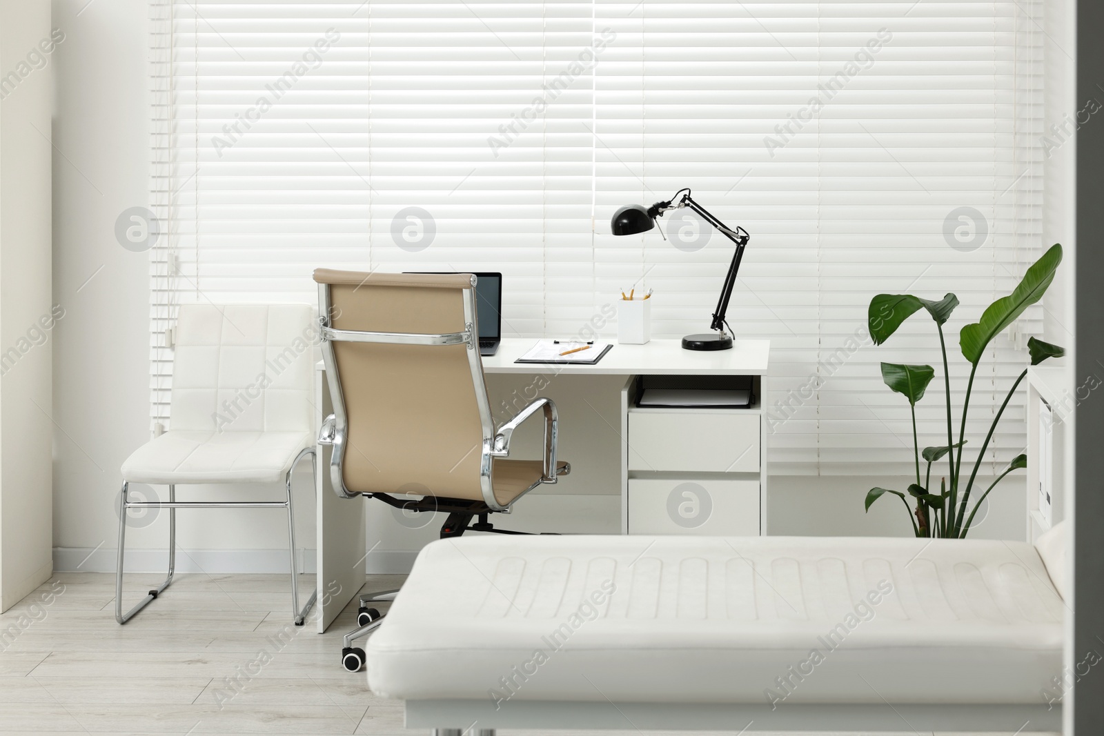 Photo of Modern medical office with doctor's workplace and examination table in clinic