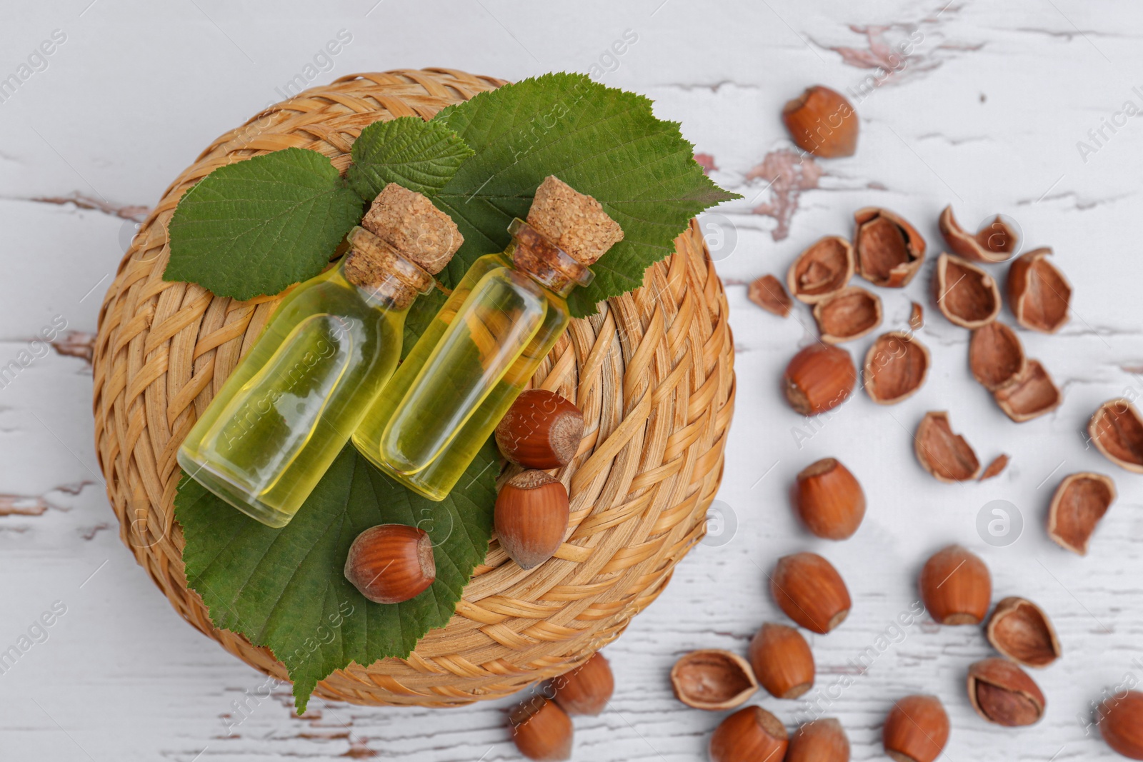 Photo of Bottles of hazelnut essential oil and nuts on wooden table, flat lay