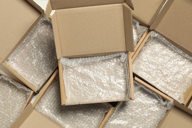 Photo of Many open cardboard boxes with bubble wrap on white wooden background, flat lay. Packaging goods