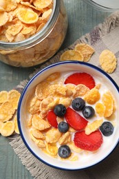 Delicious crispy cornflakes with milk and fresh berries on light blue wooden table, flat lay