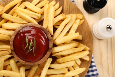 Photo of Delicious french fries served with ketchup on wooden table, flat lay