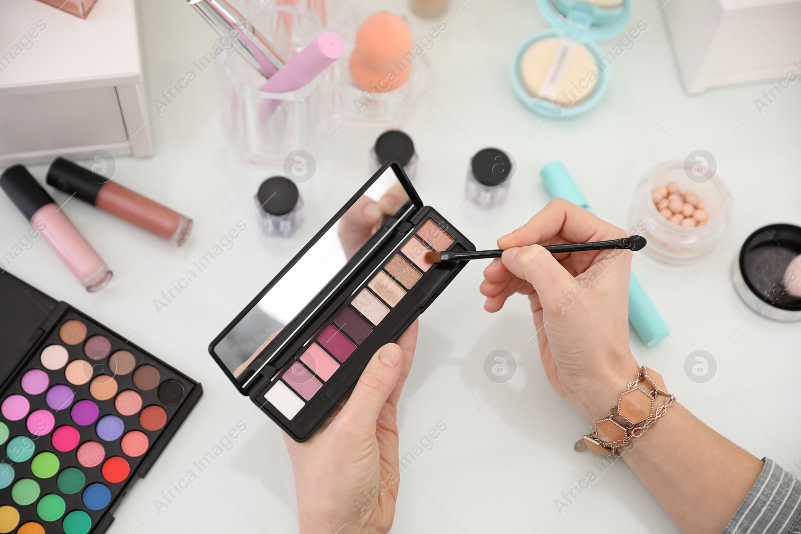 Photo of Woman applying makeup at dressing table, closeup