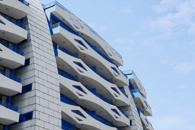 Photo of Exterior of beautiful building with balconies against blue sky, low angle view. Space for text