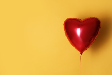 Photo of Festive heart shaped balloon on yellow background. Space for text
