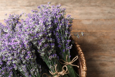 Fresh lavender flowers in basket on wooden table, closeup. Space for text