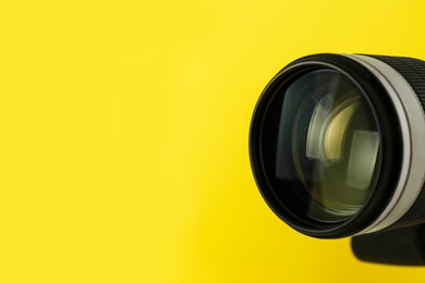 Professional video camera on yellow background, closeup view of lens. Space for text