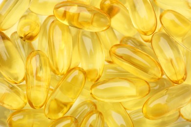 Yellow vitamin capsules as background, top view