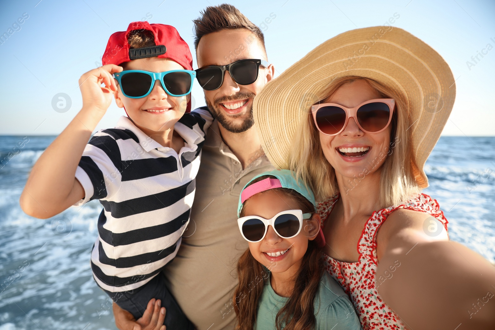 Photo of Happy family taking selfie on beach near sea. Summer vacation