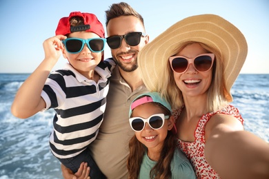 Happy family taking selfie on beach near sea. Summer vacation