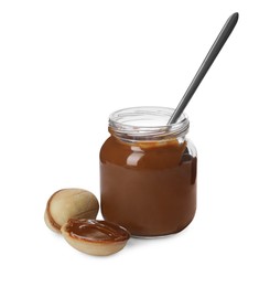 Jar with boiled condensed milk, spoon and walnut shaped cookies on white background