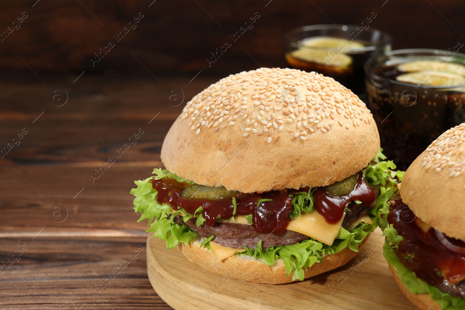 Photo of Board with delicious cheeseburgers on wooden table, closeup. Space for text