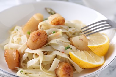 Photo of Delicious scallop pasta with lemon in bowl on table, closeup