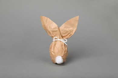 Photo of Easter bunny made of kraft paper and egg on grey background