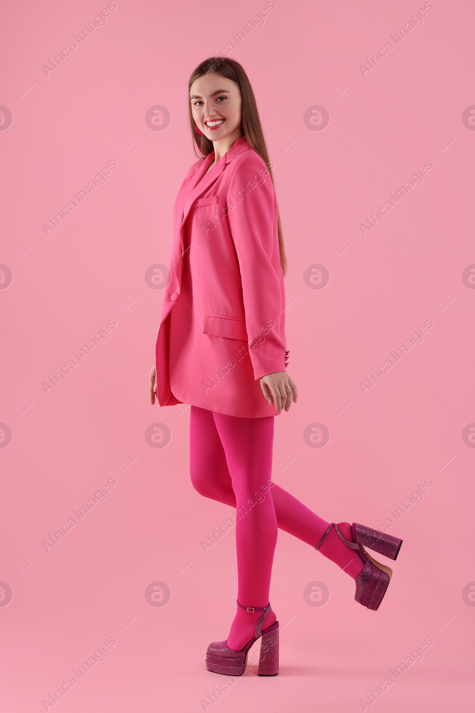 Photo of Beautiful young woman in pink clothes on color background