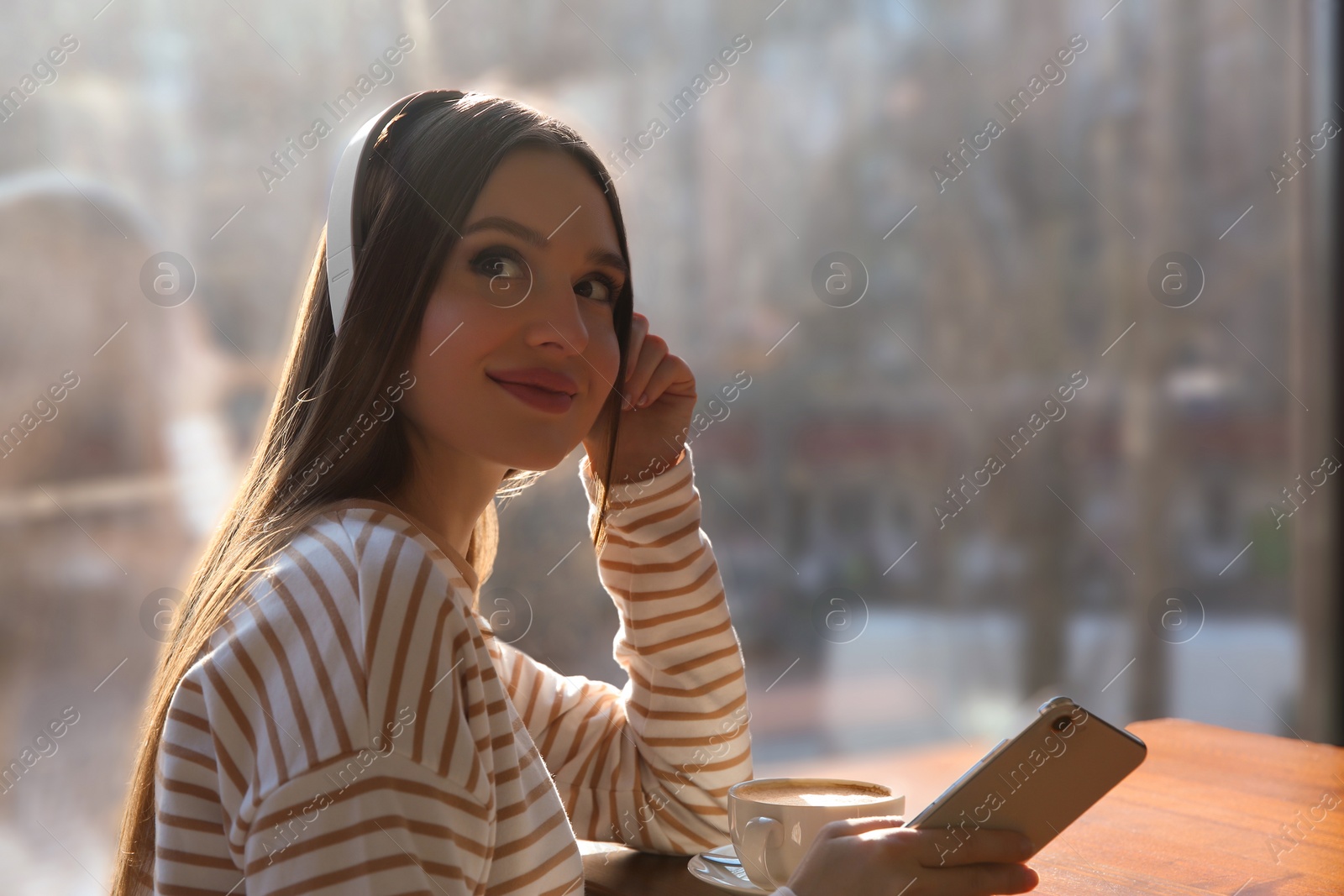 Photo of Woman listening to audiobook at table in cafe