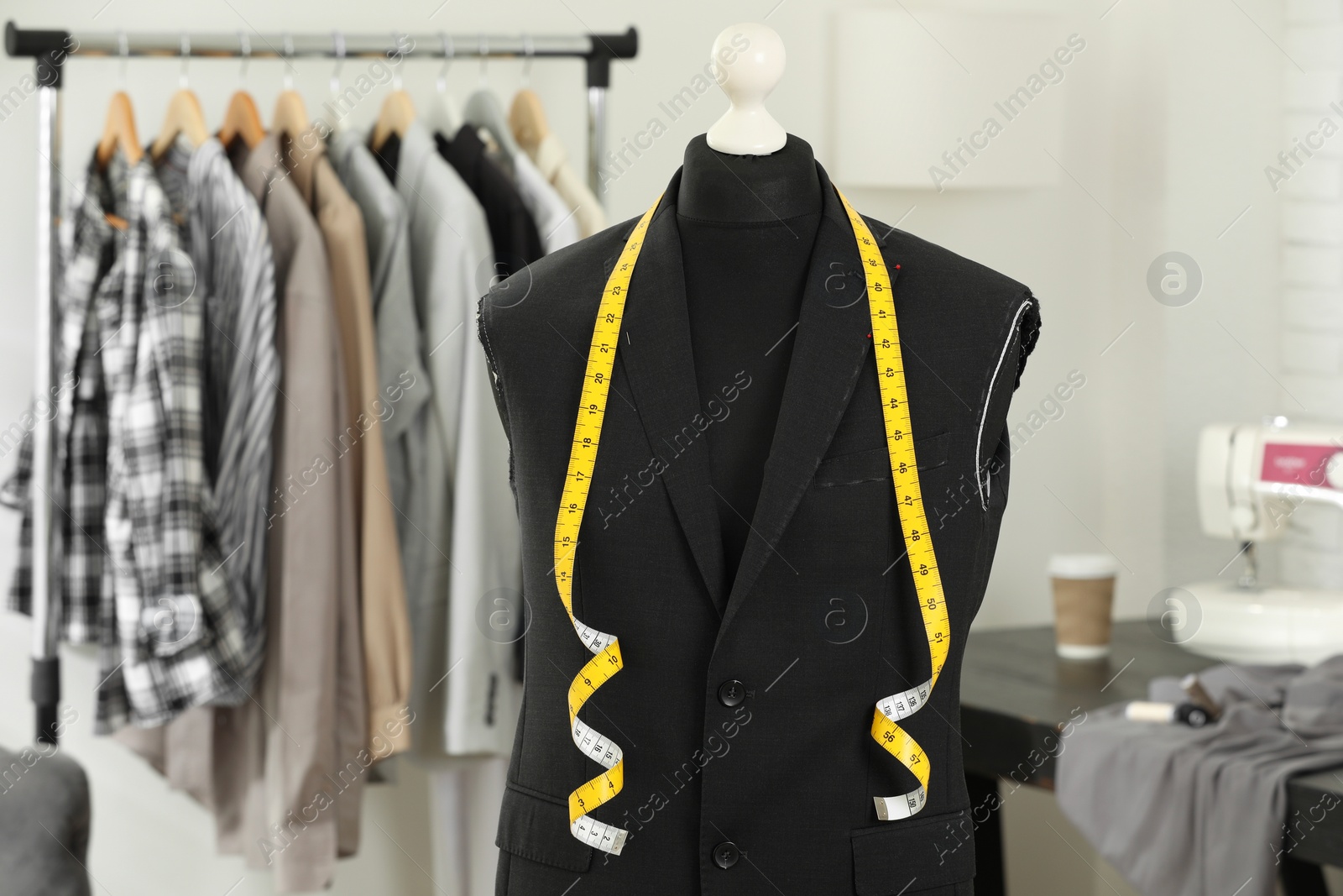 Photo of Mannequin with unfinished jacket and measuring tape in tailor shop