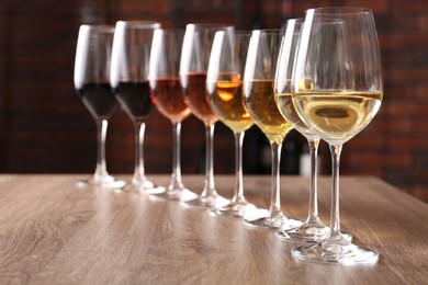 Different tasty wines in glasses on wooden table