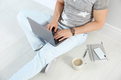 Young man with laptop sitting on floor