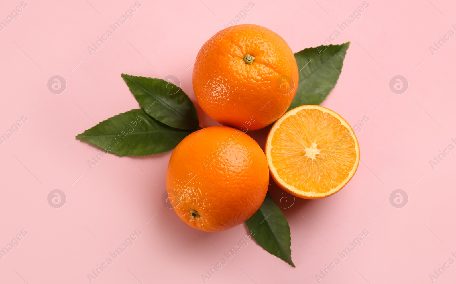 Photo of Fresh ripe oranges with green leaves on pink background, flat lay