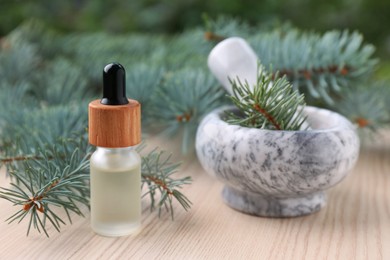 Photo of Pine essential oil and branches on white wooden table, closeup