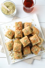 Photo of Delicious fresh baklava with chopped nuts served on white wooden table, flat lay. Eastern sweets