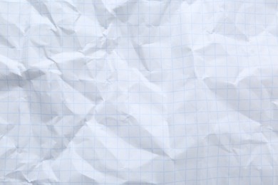 Crumpled checkered notebook sheet as background, top view