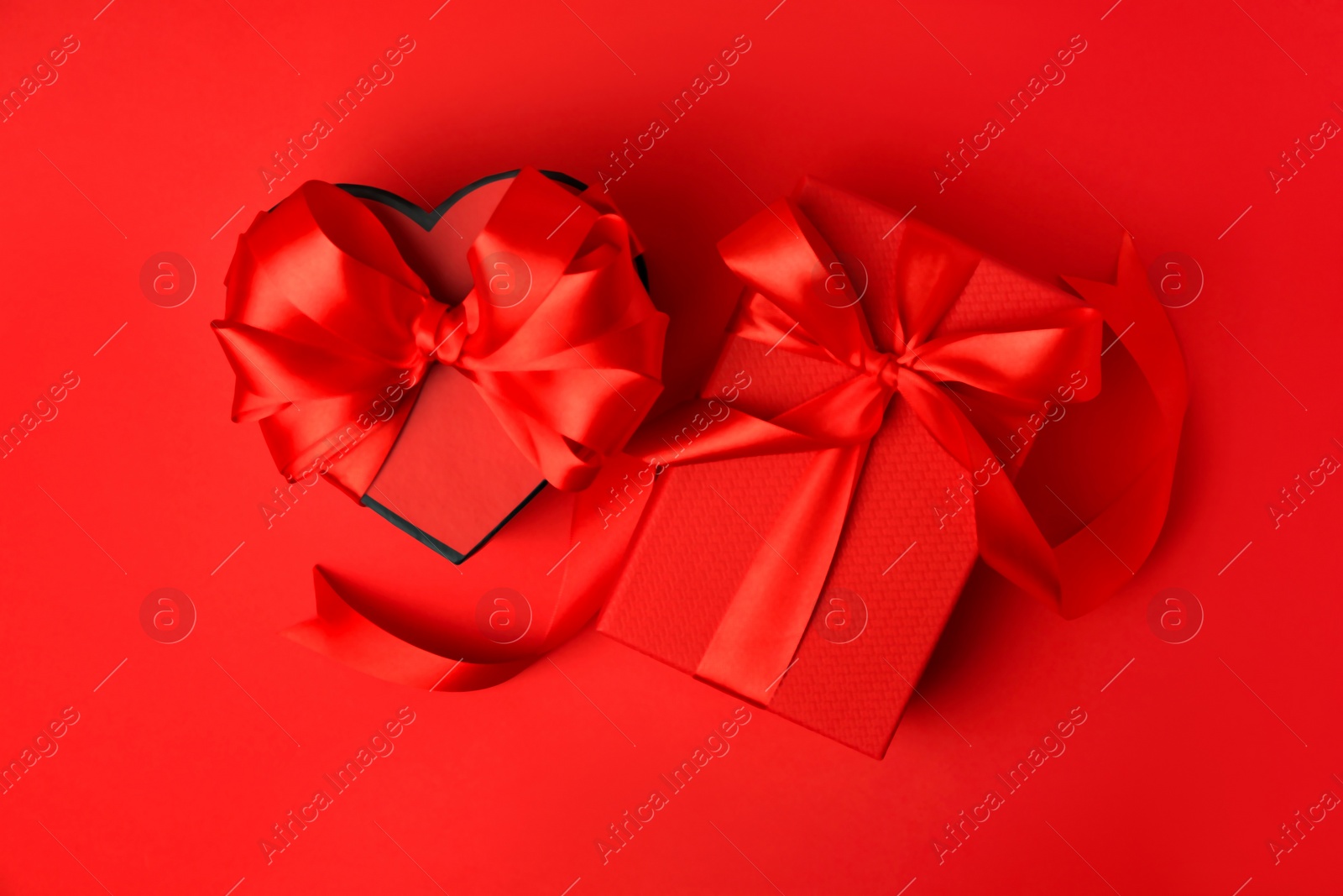Photo of Beautiful gift boxes with bows on red background, flat lay
