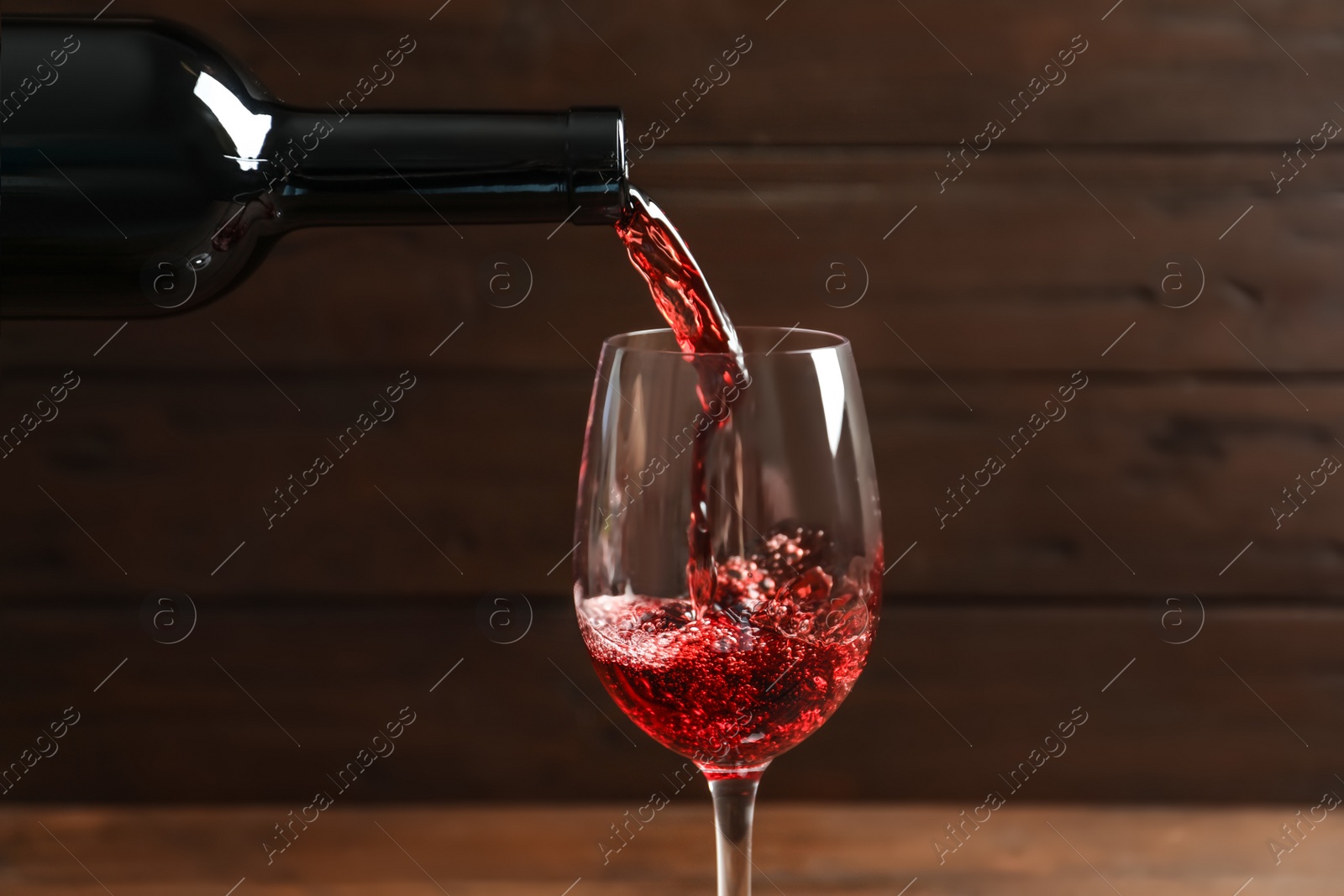 Photo of Pouring delicious red wine into glass on blurred background