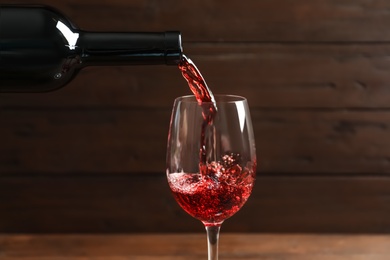 Photo of Pouring delicious red wine into glass on blurred background