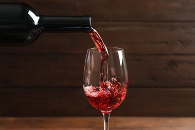 Pouring delicious red wine into glass on blurred background