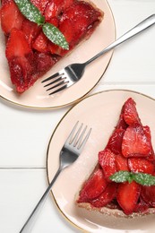 Pieces of delicious strawberry tart with mint on white wooden table, flat lay