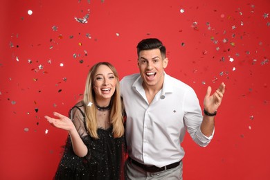 Photo of Happy couple and confetti on red background