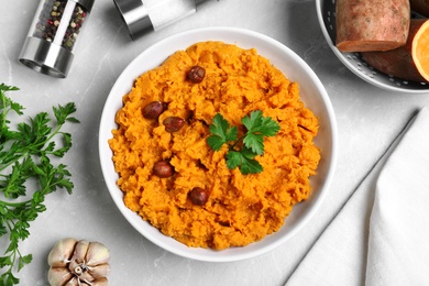 Flat lay composition with bowl of sweet potato puree on grey table