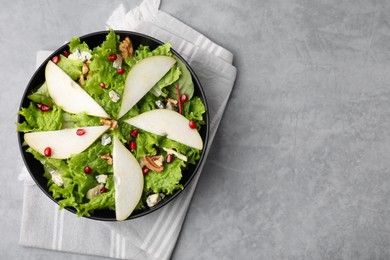 Delicious pear salad in bowl on grey textured table, top view. Space for text